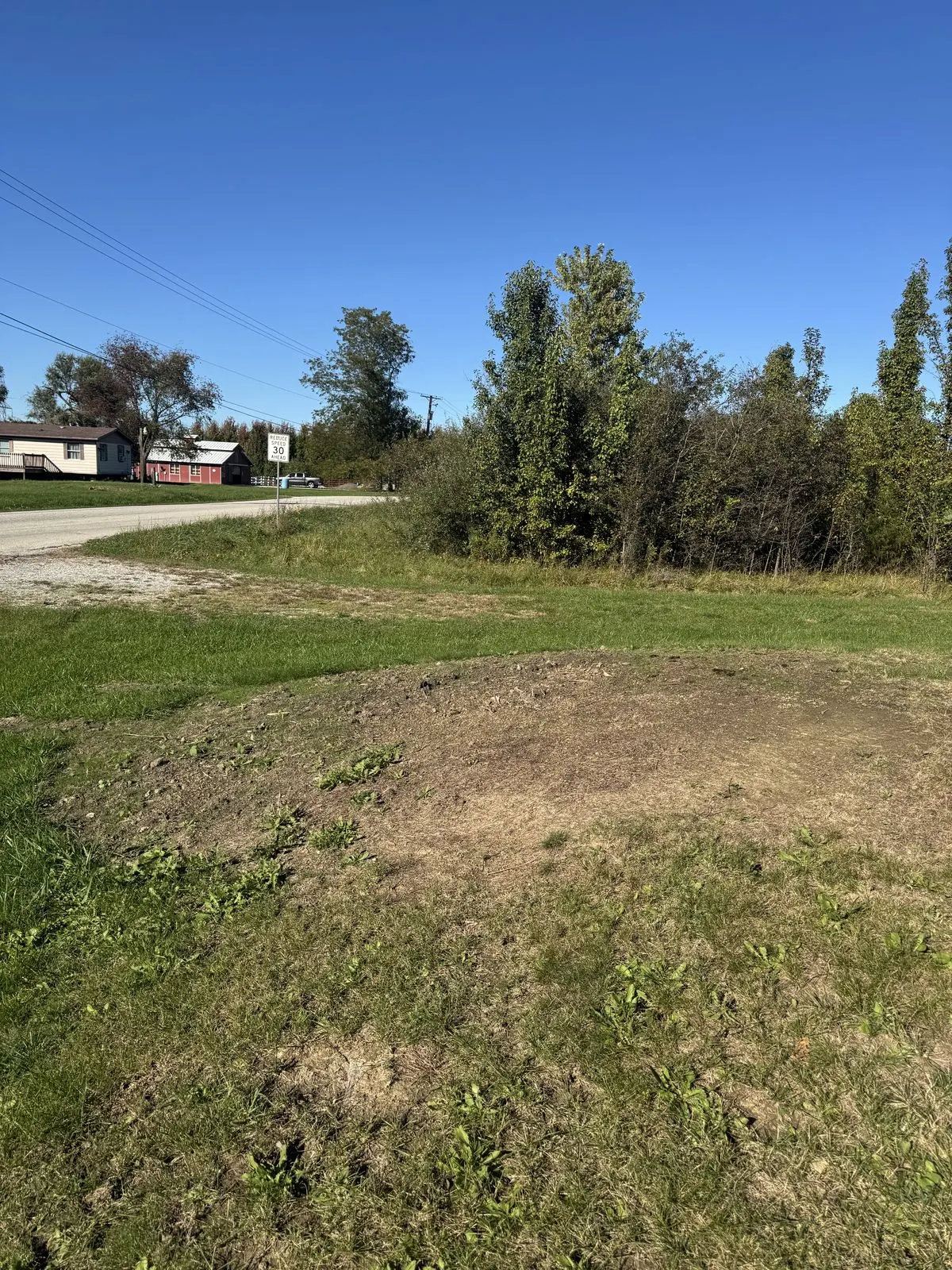 The same spot by the road after the job, the stump and brush gone and the ground filled and leveled